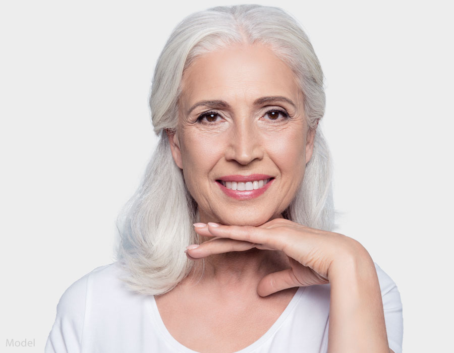 Mature white haired woman with her hand under her chin